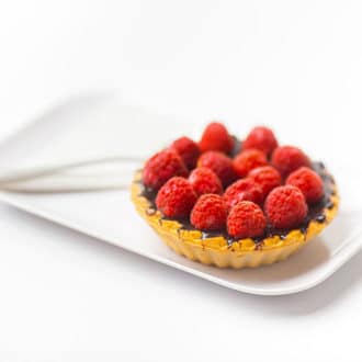 Raspberry and chocolate tart on a white plate