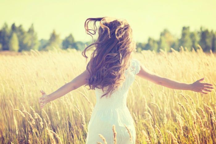 Girl with long brown hair running through field