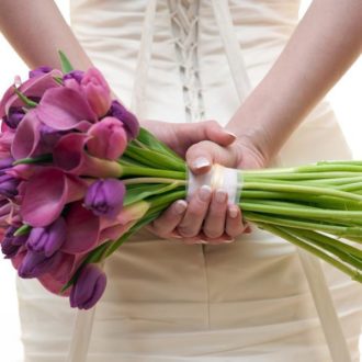 bride holding wedding flower bouquet behind back