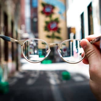 person holding glasses against city