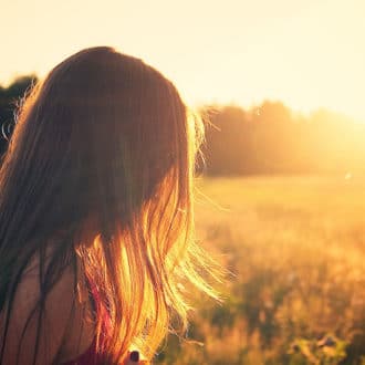Girl in field with sunset and long hair