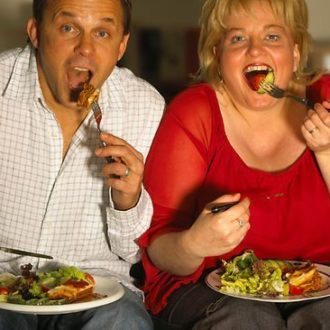 man and woman eating dinner on couch