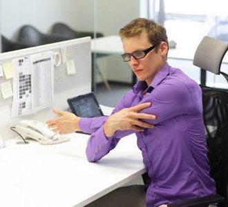 Man stretching at office desk