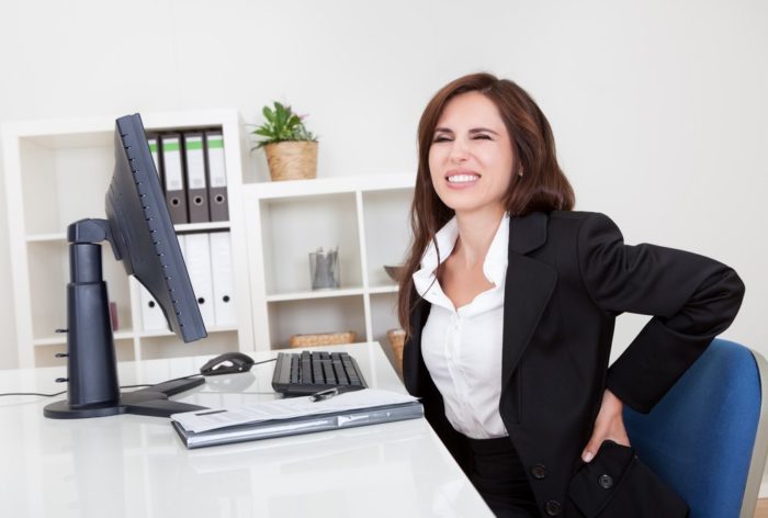 Business woman sitting at computer desk with sore back