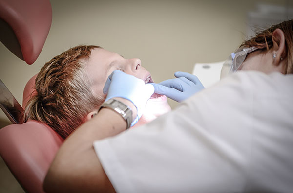 Dentist inspecting boys teeth in dental chair