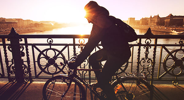 Man riding bike over bridge