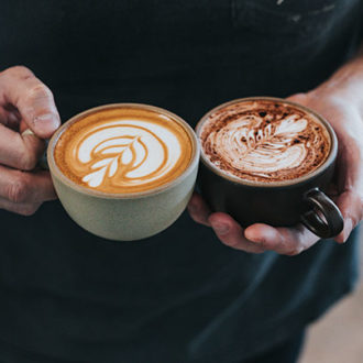 person holding flat white and cappacino