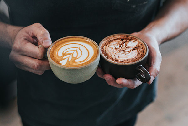 person holding flat white and cappacino