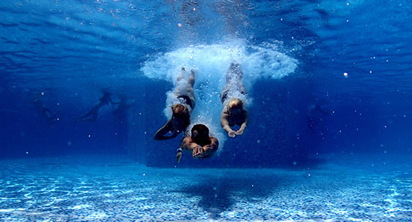 three people diving in pool
