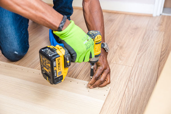 Handyman carpenter using drill on timber floor