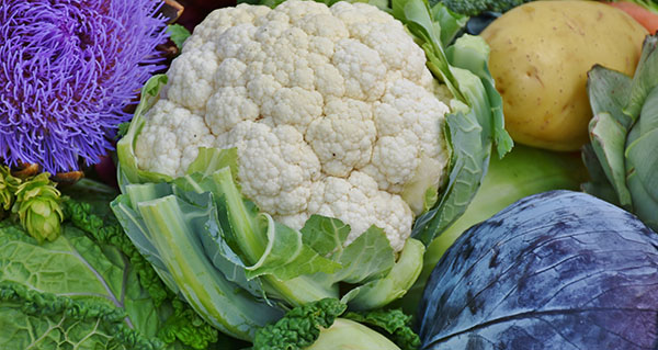 Head of cauliflower surrounded by vegetables