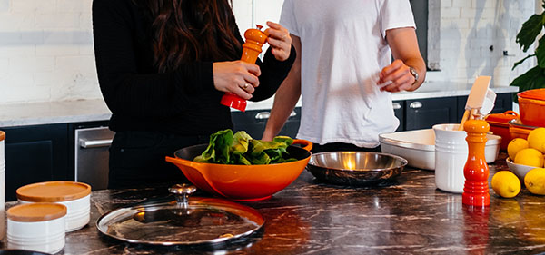 man and woman making salad in kitchen