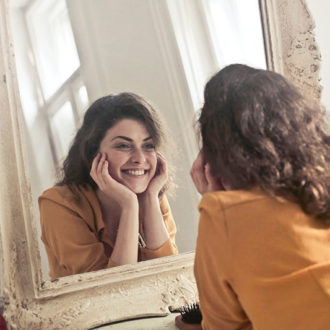 Happy girl looking at skin in mirror