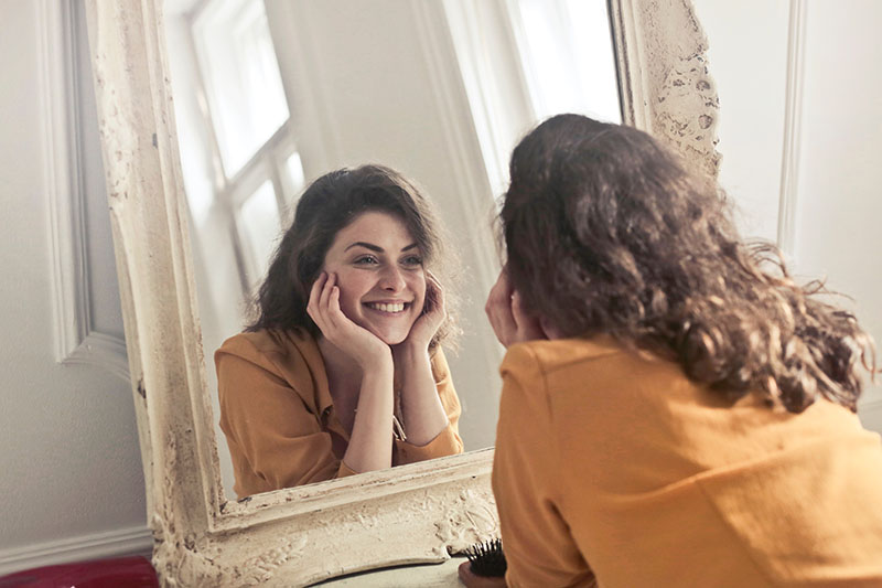 Happy girl looking at skin in mirror