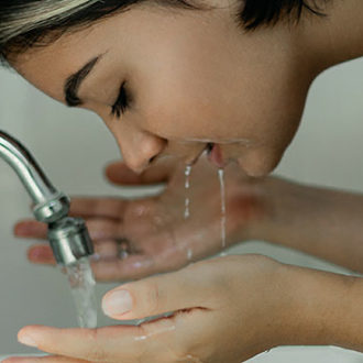 girl washing face in sink