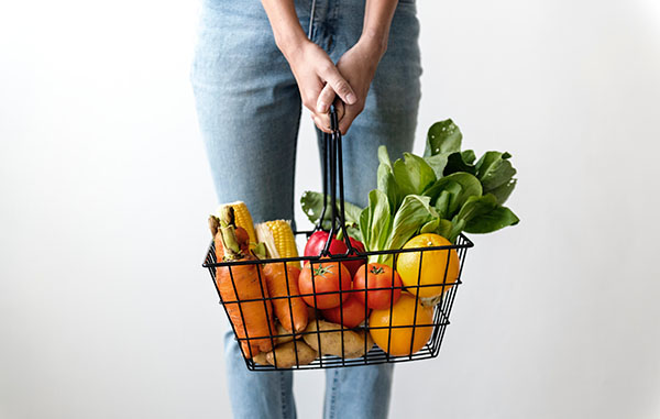 Woman holding basket of fruit and vegetables for vegan food