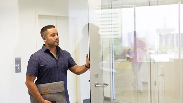 Man holding glass door in office open