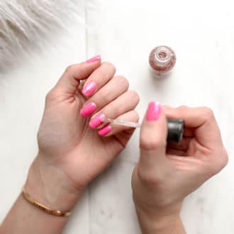 Hands painting nails with pink nail polish