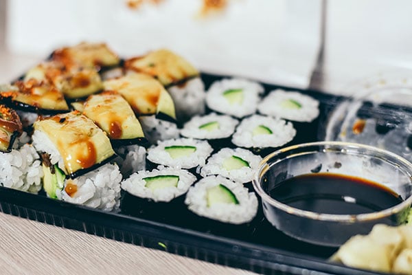 plate of sushi rolls with avocado sushi and soy sauce