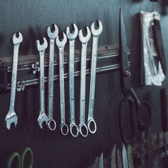 Different sized wrenches and tools hanging on wall