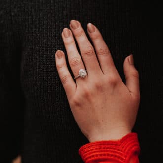 womans hand with diamond engagement ring resting on black background