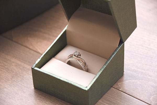 green ring box with silver diamond engagement ring on table
