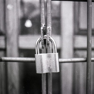 black and white image of door with security bars and padlock