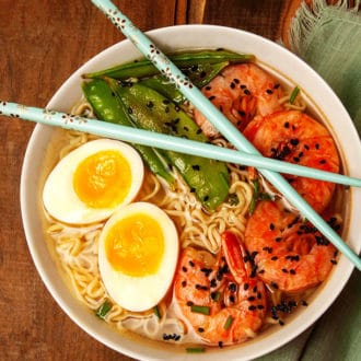 bowl of ramen soup with eggs and prawns and chopsticks