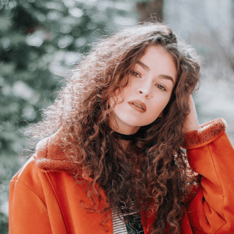Girl with brown hair and a orange coat