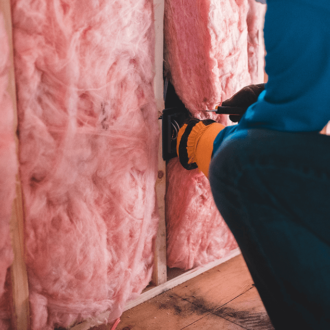 Pink bulk insulation being installed